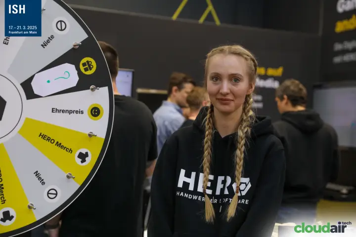 Portrait next to the HERO prize wheel at ISH 2025