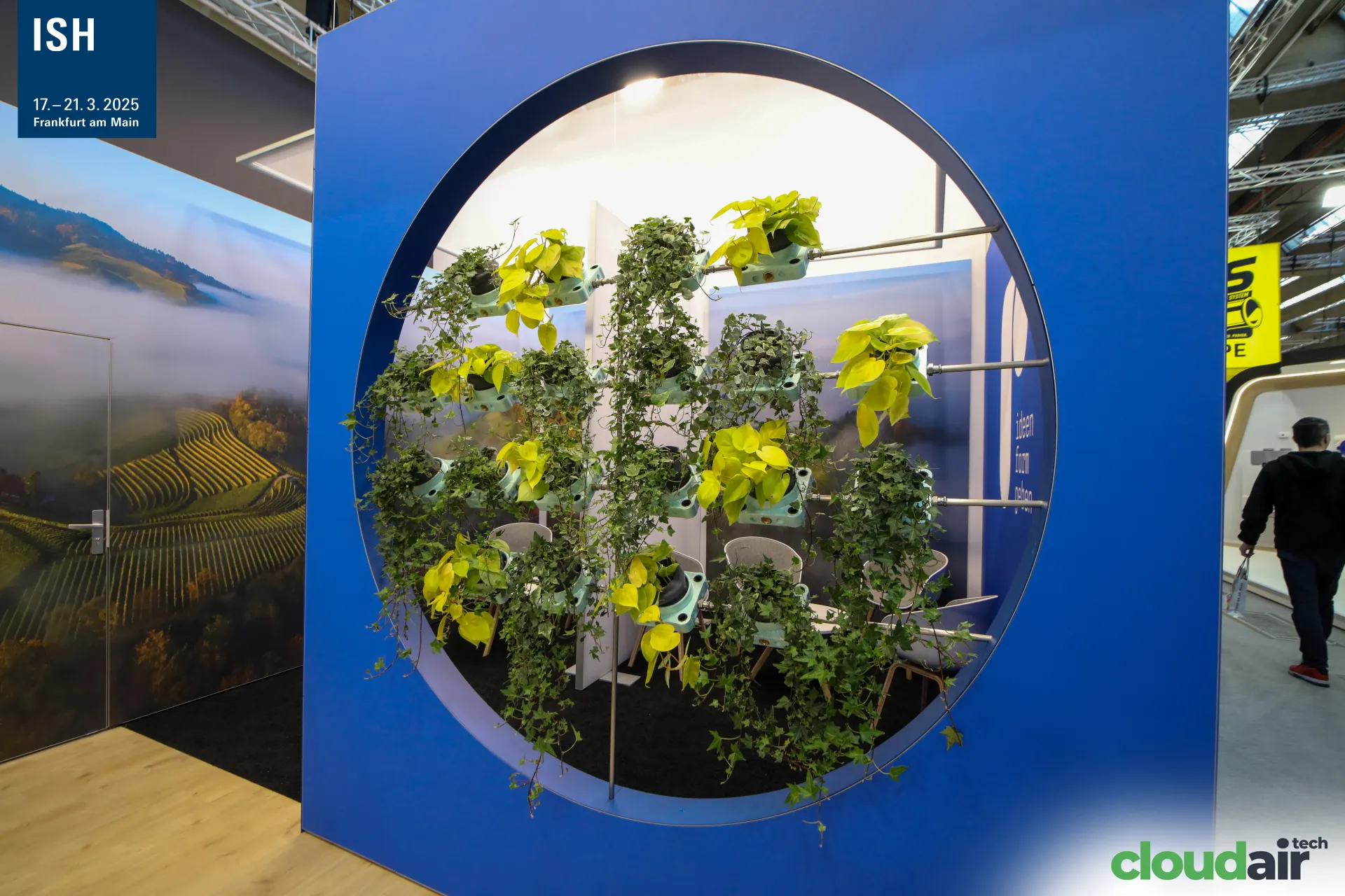 Ruch Novaplast blue wall with circular opening filled with plants at ISH 2025