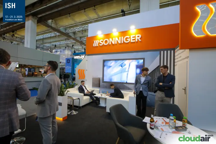 Sonniger lounge with white sofas and video screen under orange fascia at ISH 2025