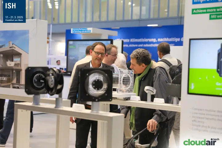Visitors discussing compact fans displayed on white rails at ebm-papst at ISH 2025