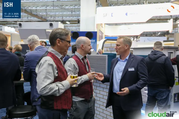 Visitors with drinks in conversation at the TROX stand at ISH 2025