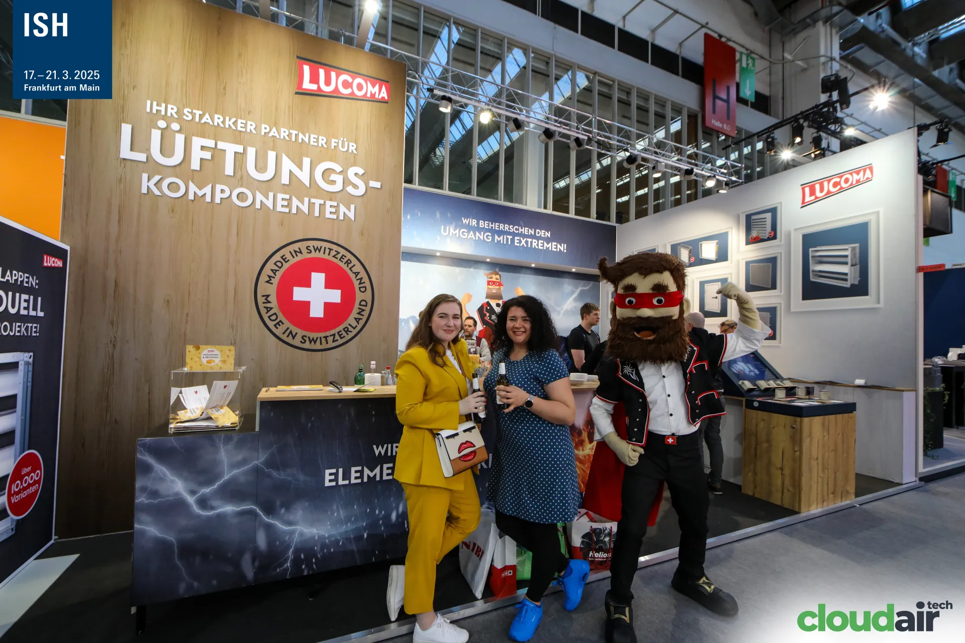 Visitors pose with the Lucoma superhero mascot at the counter at ISH 2025