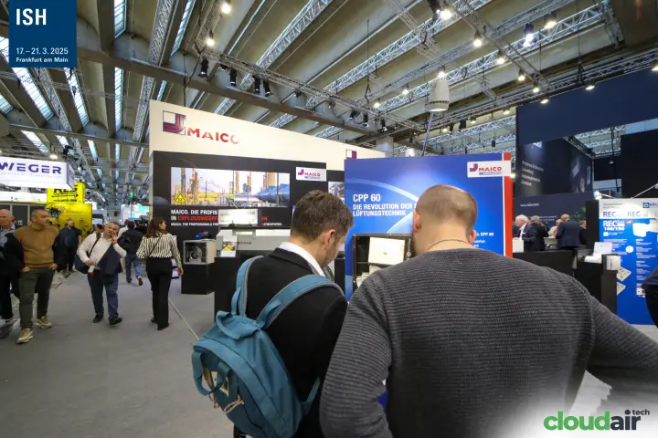 Visitors studying the Maico CPP 60 panel next to the stand's fan wall
