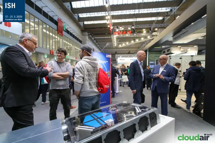 Visitors talking beside a Maico ventilation unit with transparent cover at ISH 2025