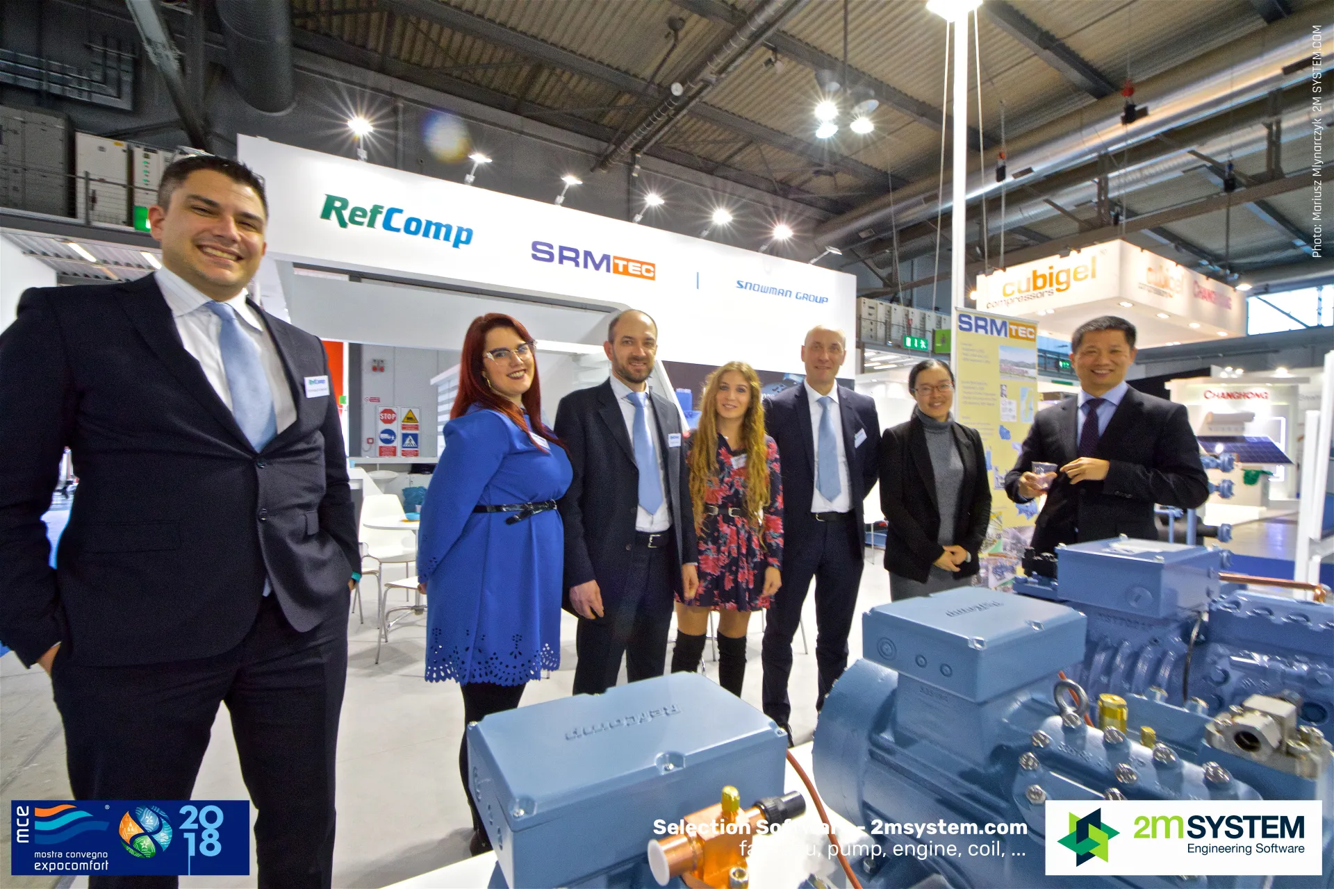 Smiling RefComp group beside blue semi-hermetic compressors at MCE 2018