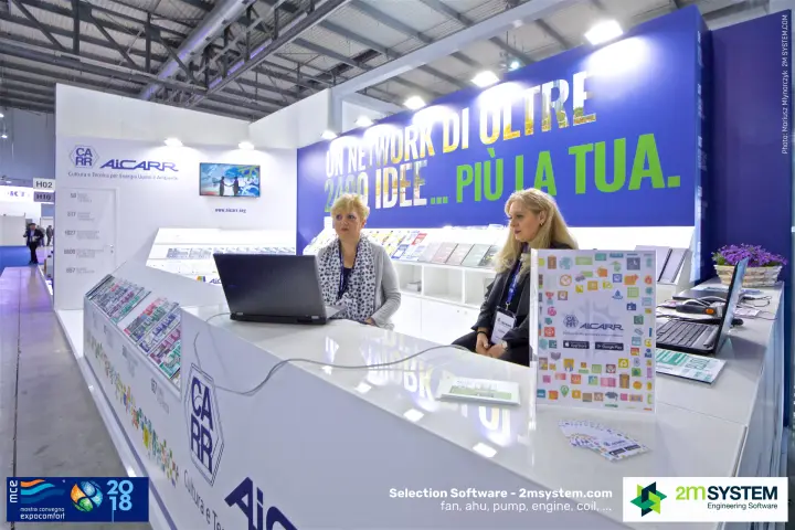 Staff at the AiCARR reception counter in front of the blue slogan wall at MCE 2018