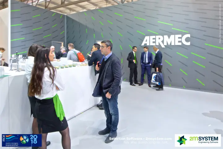 Visitors at the Aermec bar counter in front of the grey logo wall at MCE 2018