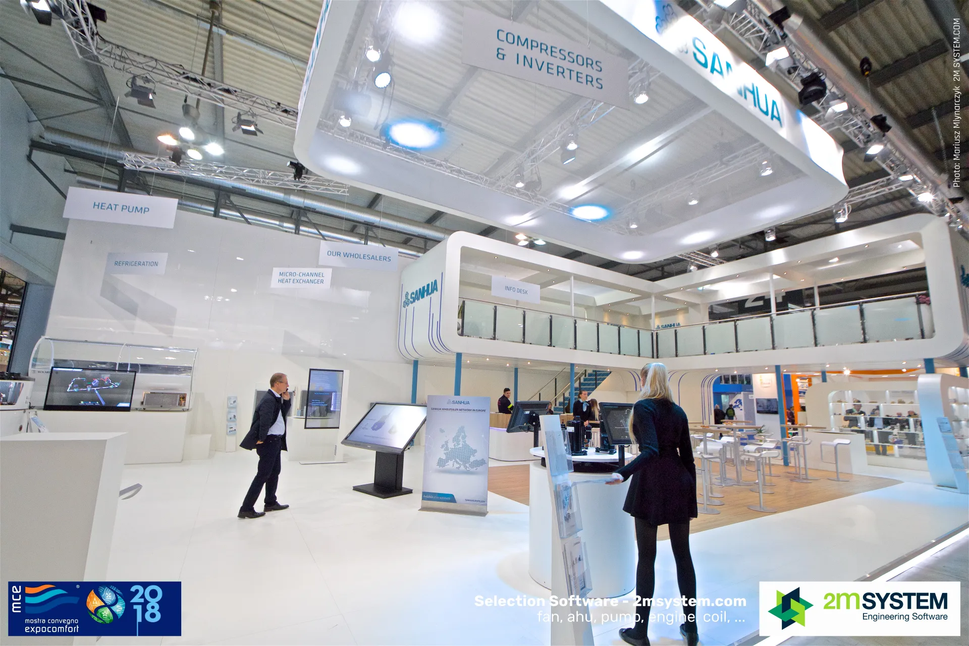 Visitors at Sanhua touchscreen kiosks below the upper deck at MCE 2018
