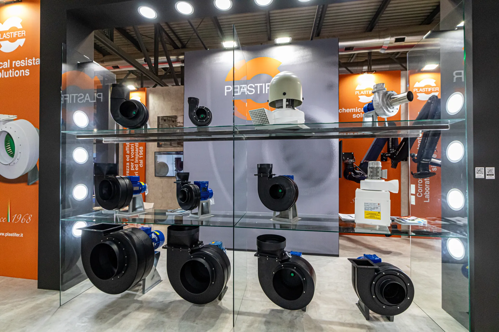 Black plastic centrifugal fans and a roof fan on Plastifer's glass display at MCE 2024