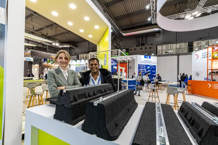 Black rubber support blocks with metal rails on a lime-yellow stand counter at MCE 2024