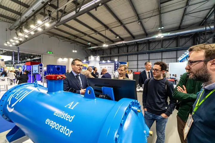 Blue AI assisted evaporator close up with visitors gathered around it