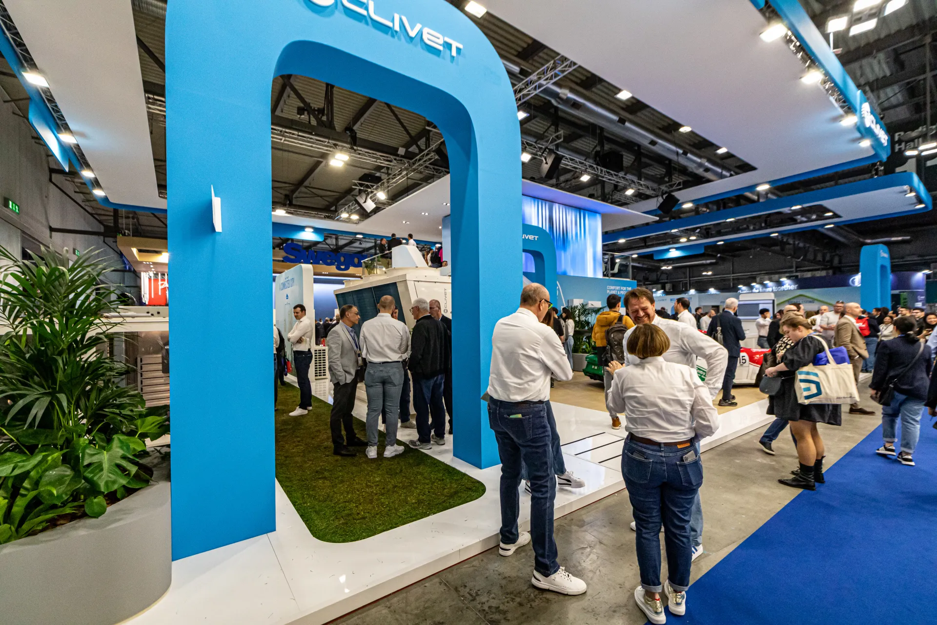Blue arched entrance with Clivet logo leading onto a grass-floored stand at MCE 2024