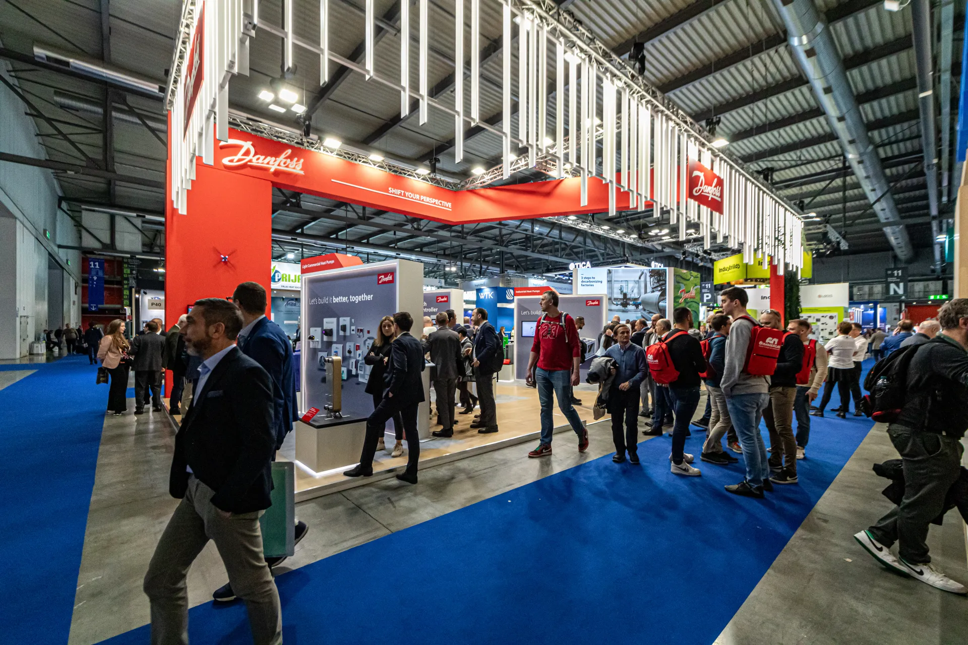 Busy aisle along the red Danfoss stand with heat pump displays at MCE 2024