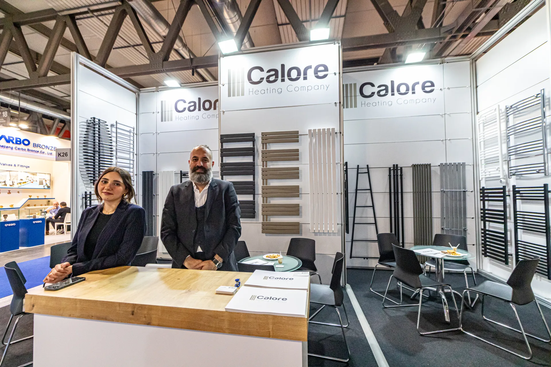 Calore reception counter with brochures in front of a wall of towel radiators at MCE 2024