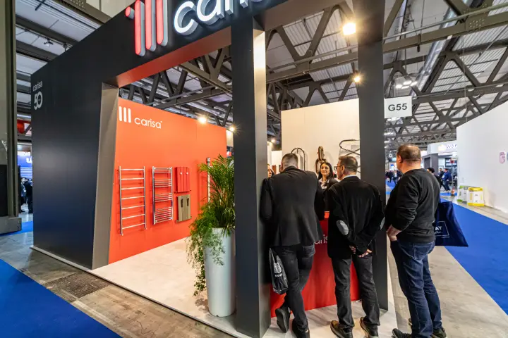 Carisa stand with illuminated logo and towel radiators on a red wall at MCE 2024