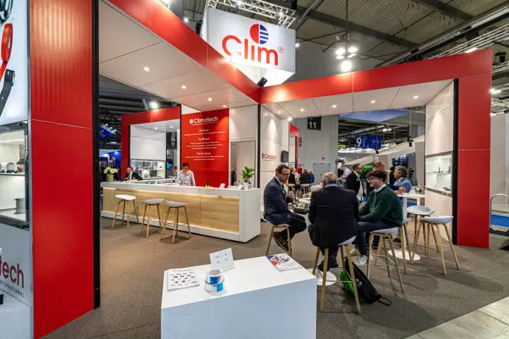 Climatech stand with red portal frames and a wood-fronted counter at MCE 2024