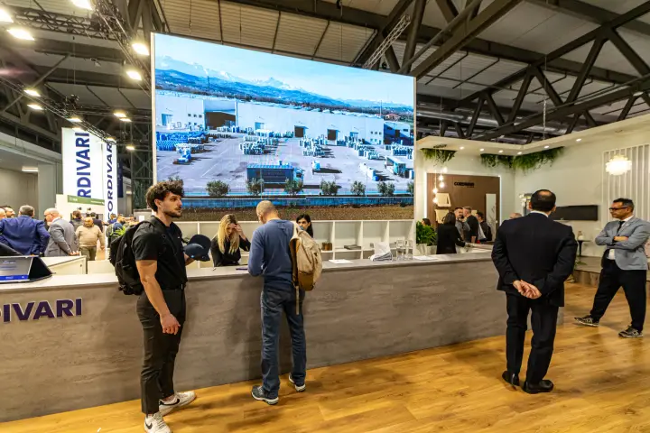 Cordivari reception counter under an LED wall showing the factory from above at MCE 2024