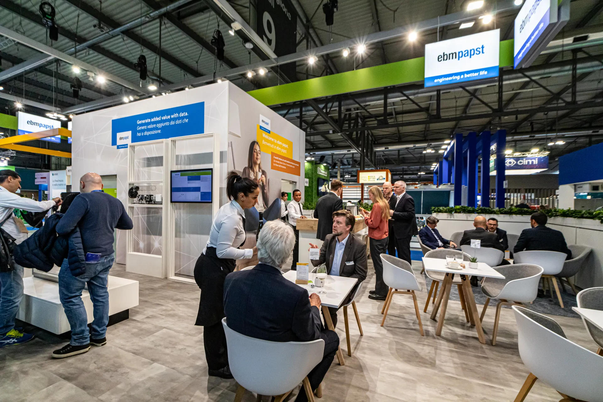 ebm-papst lounge with café tables beside the data and welcome walls at MCE 2024