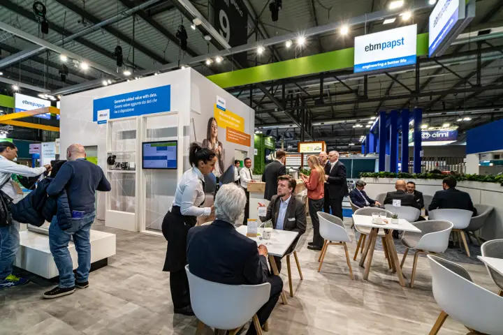 ebm-papst lounge with café tables beside the data and welcome walls at MCE 2024