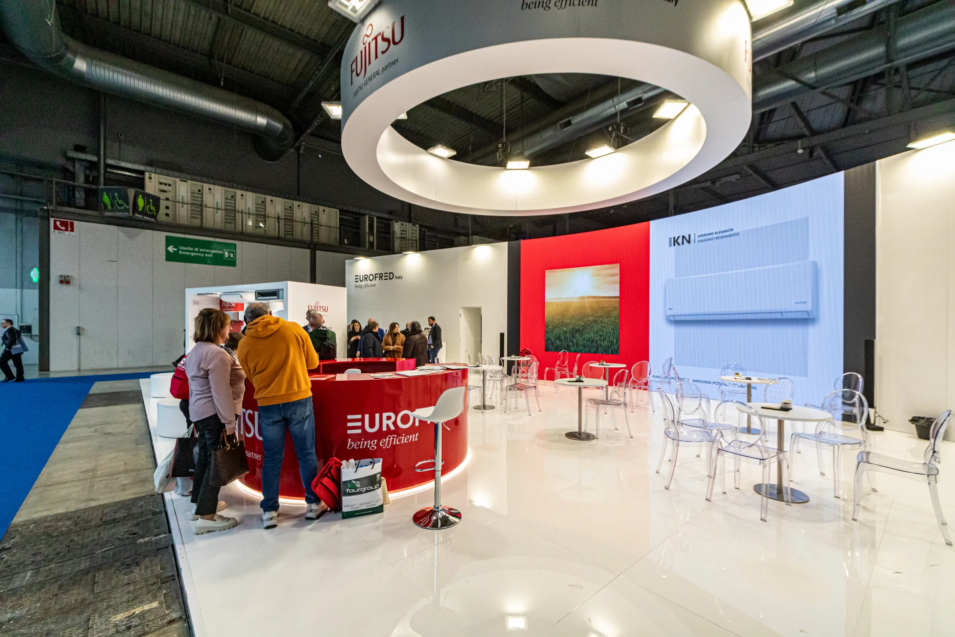 Eurofred red reception counter and seating area under a suspended Fujitsu ring at MCE 2024