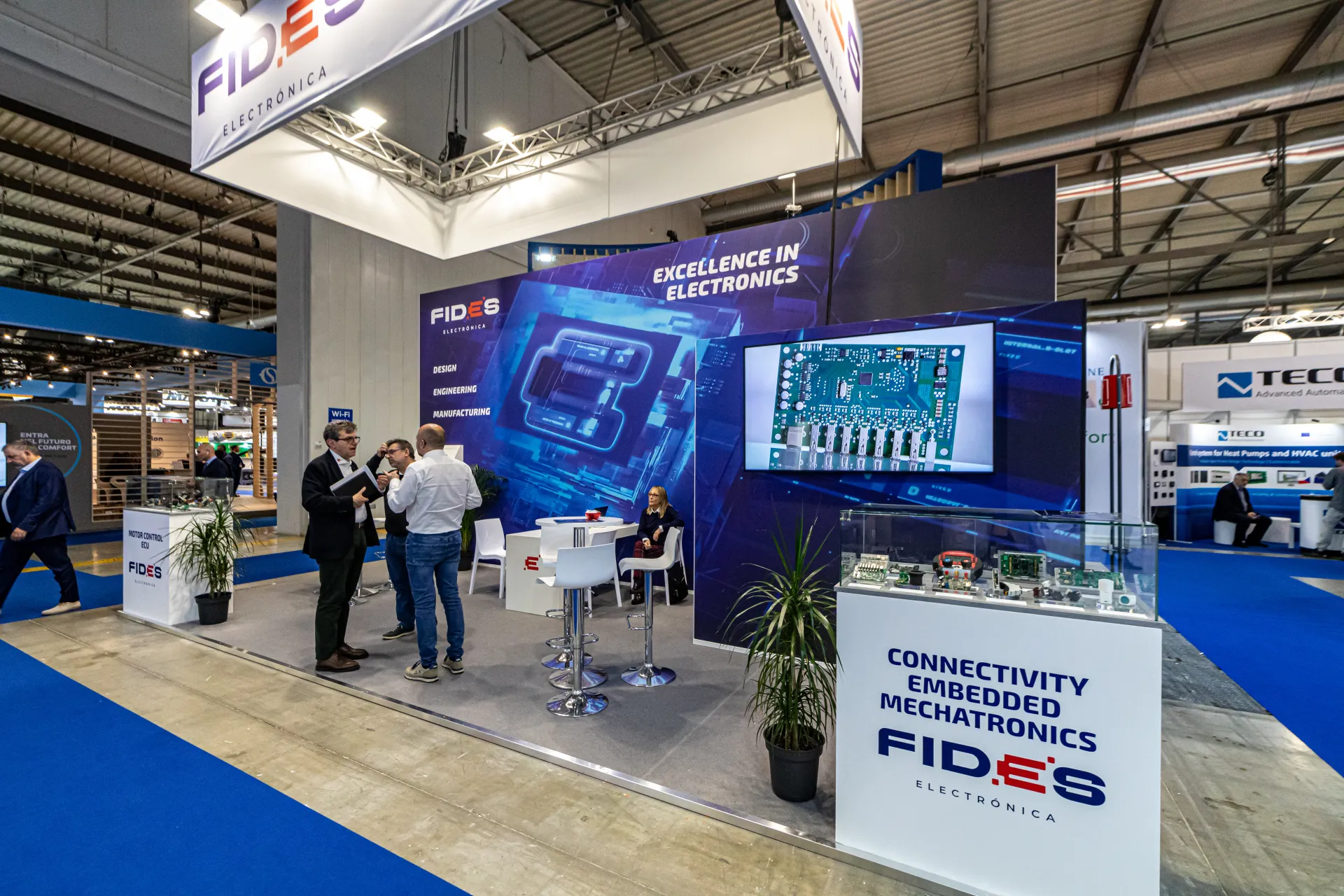 Fides Electrónica hanging banner and circuit board on screen at MCE 2024