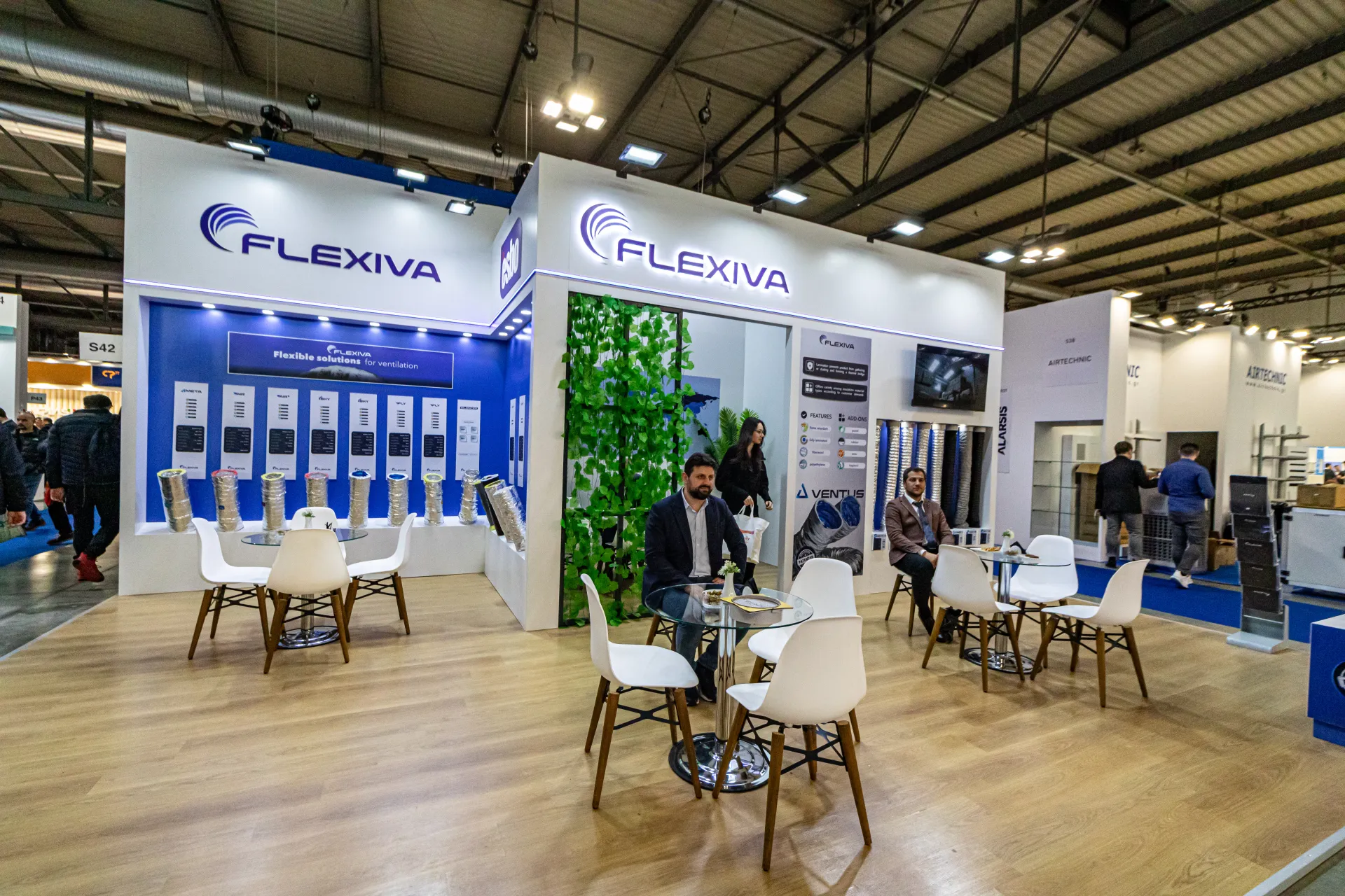 Flexiva stand with flexible duct rolls and a greenery-framed entrance at MCE 2024
