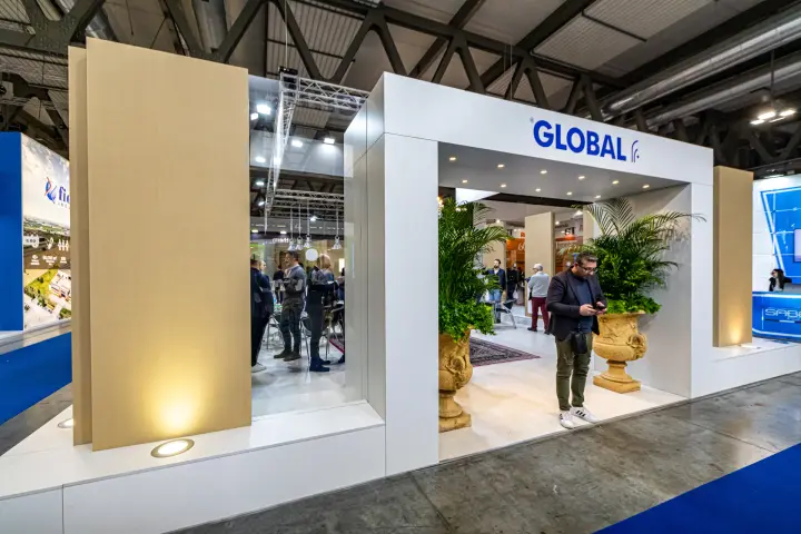 Global stand with white portal, beige panels and palms in urns