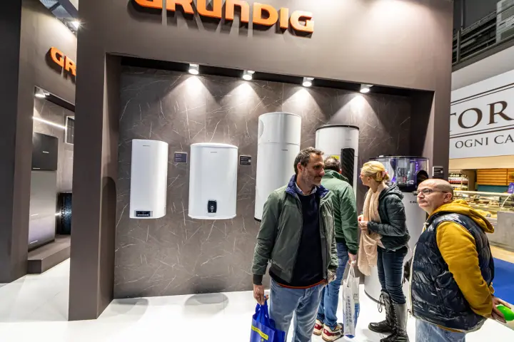 Grundig electric and heat pump water heaters on a dark marble-effect wall
