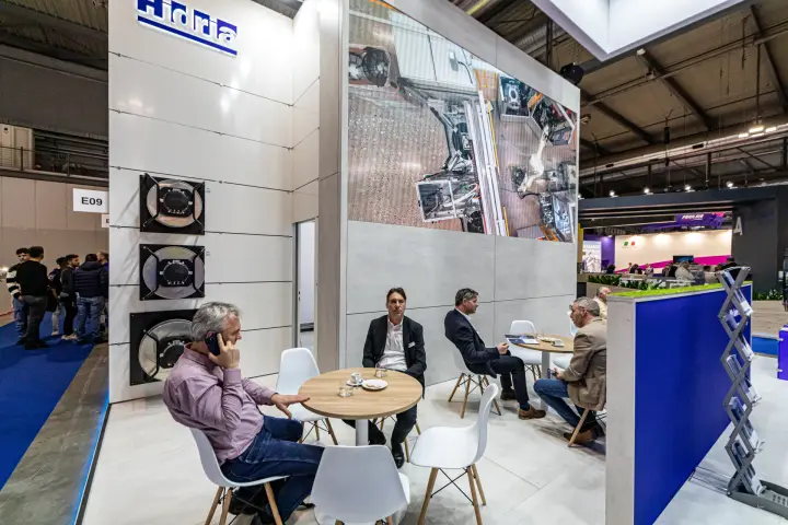 Hidria meeting area beneath a video wall showing a production line