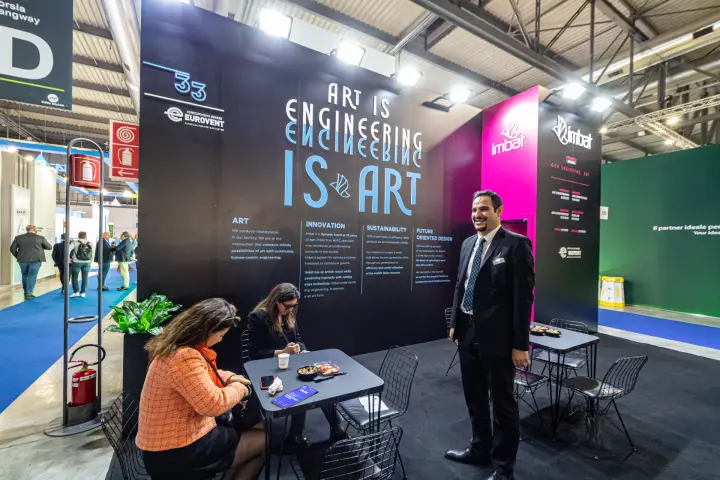 Imbat stand with 'ART IS ENGINEERING IS ART' black wall at MCE 2024