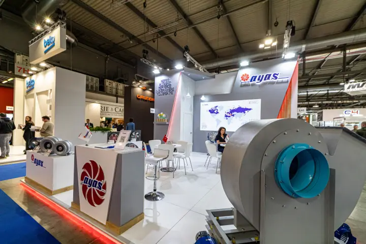 Large centrifugal fan with turquoise inlet beside Ayas logo podiums
