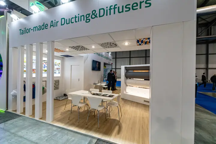 Meeting area with duct samples under a "Tailor-made Air Ducting&Diffusers" fascia