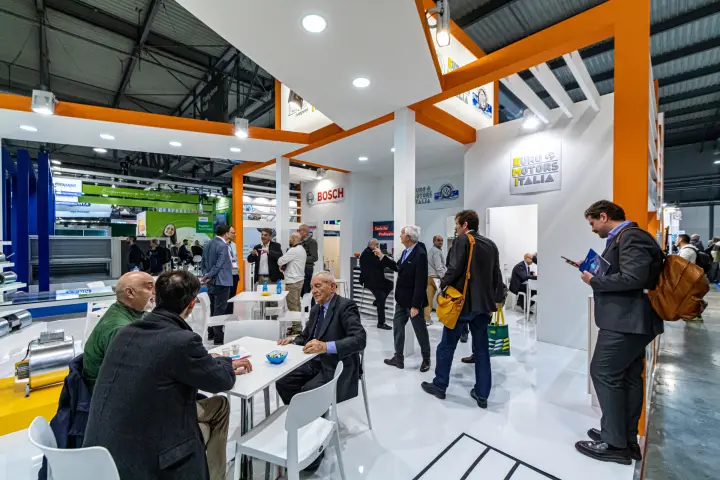 Meeting area of the Euro Motors Italia stand under orange beams at MCE 2024