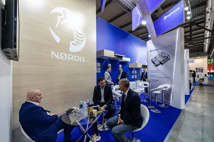 Meeting at the Nordis logo wall with indoor unit display along the aisle