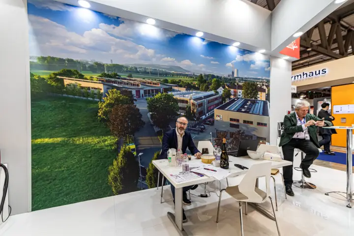 Meeting table in front of a factory photo mural on the MRU Airfair stand