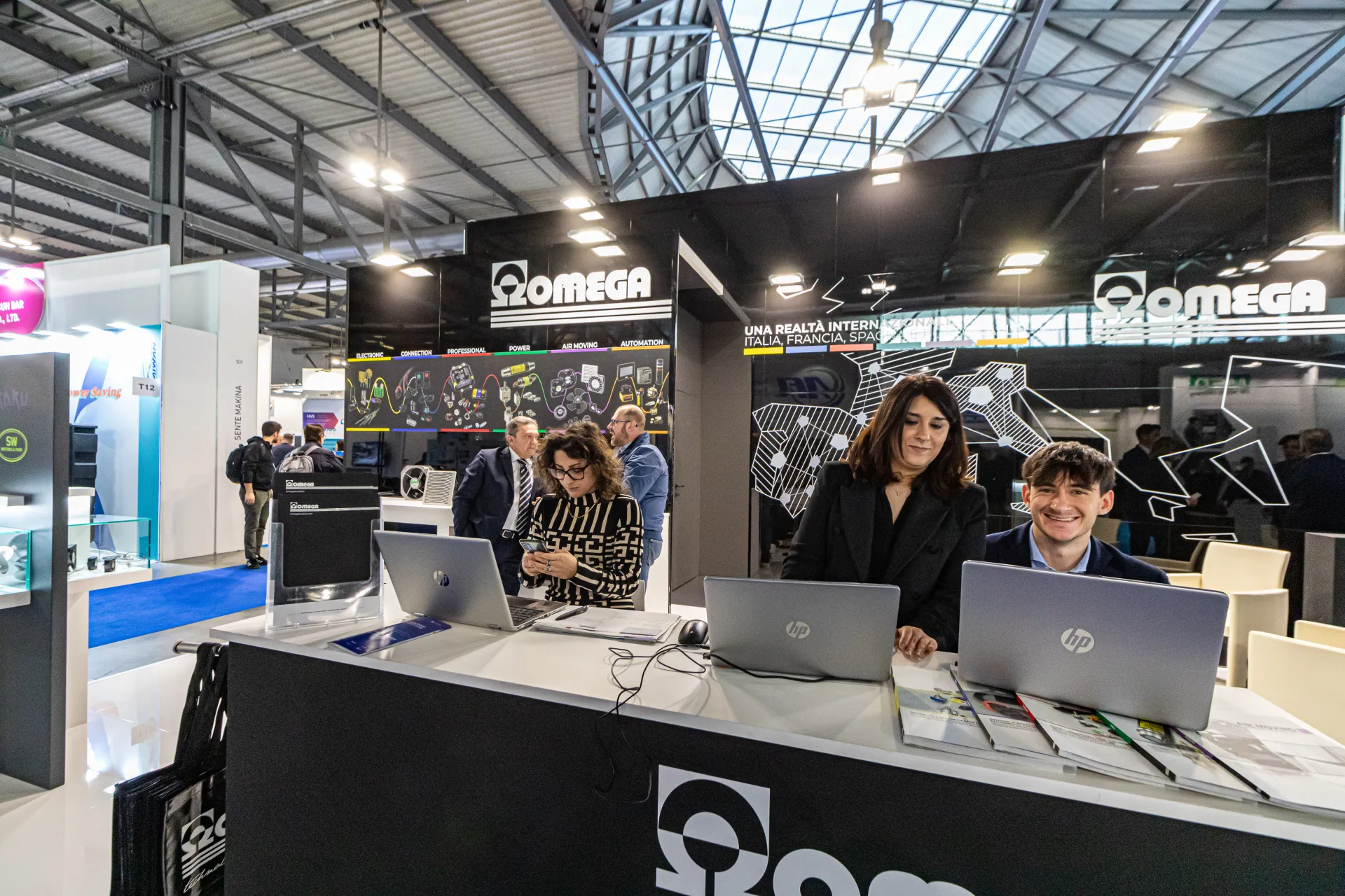 Omega reception desk with staff and international network graphic at MCE 2024