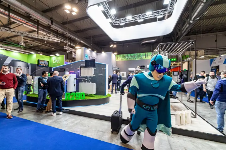 Sendo mascot greeting visitors beside the R290 system display at MCE 2024