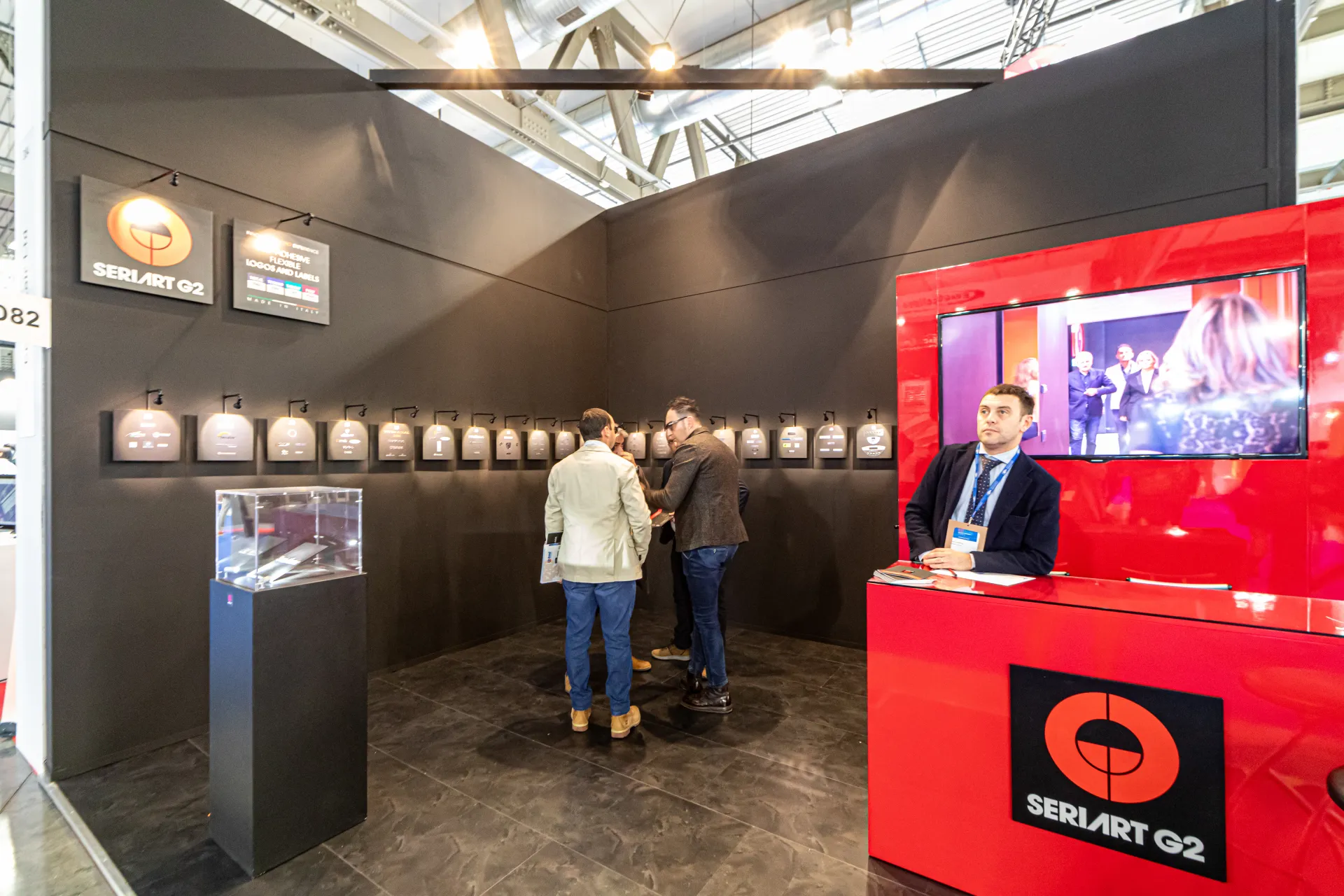 Seriart G2 stand with a lit row of adhesive logo samples on a black wall at MCE 2024