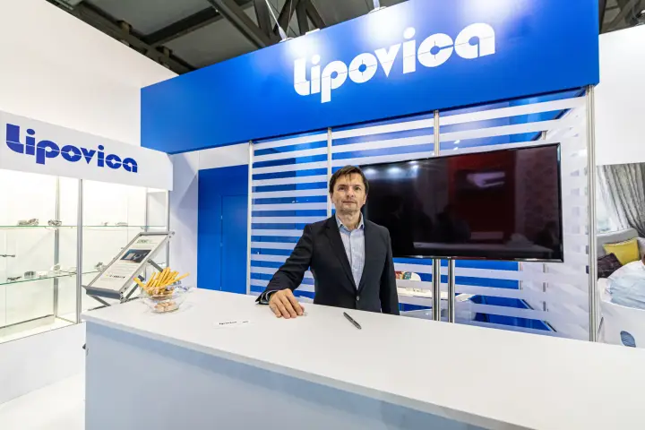 Staff member at the Lipovica counter beneath the blue logo fascia