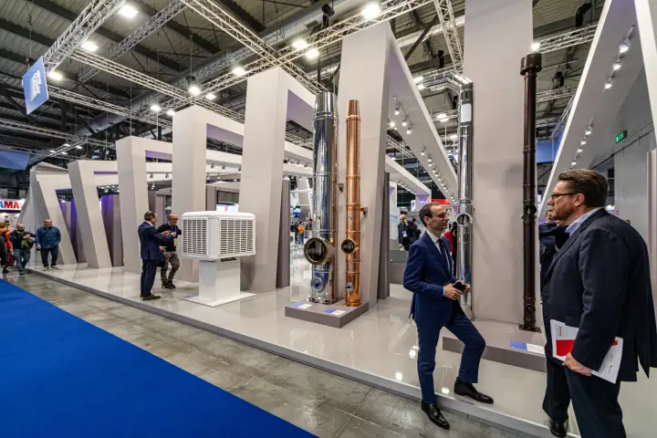 Stainless steel and copper flue pipes between tilted grey portal frames at MCE 2024