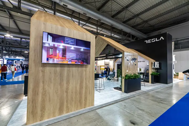Tesla stand with wooden house-shaped frames and heat pump screen at MCE 2024