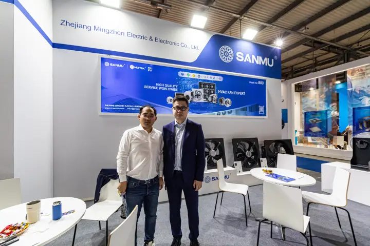 Two people at the Sanmu stand in front of the 'HVAC FAN EXPERT' back-wall graphic at MCE 2024