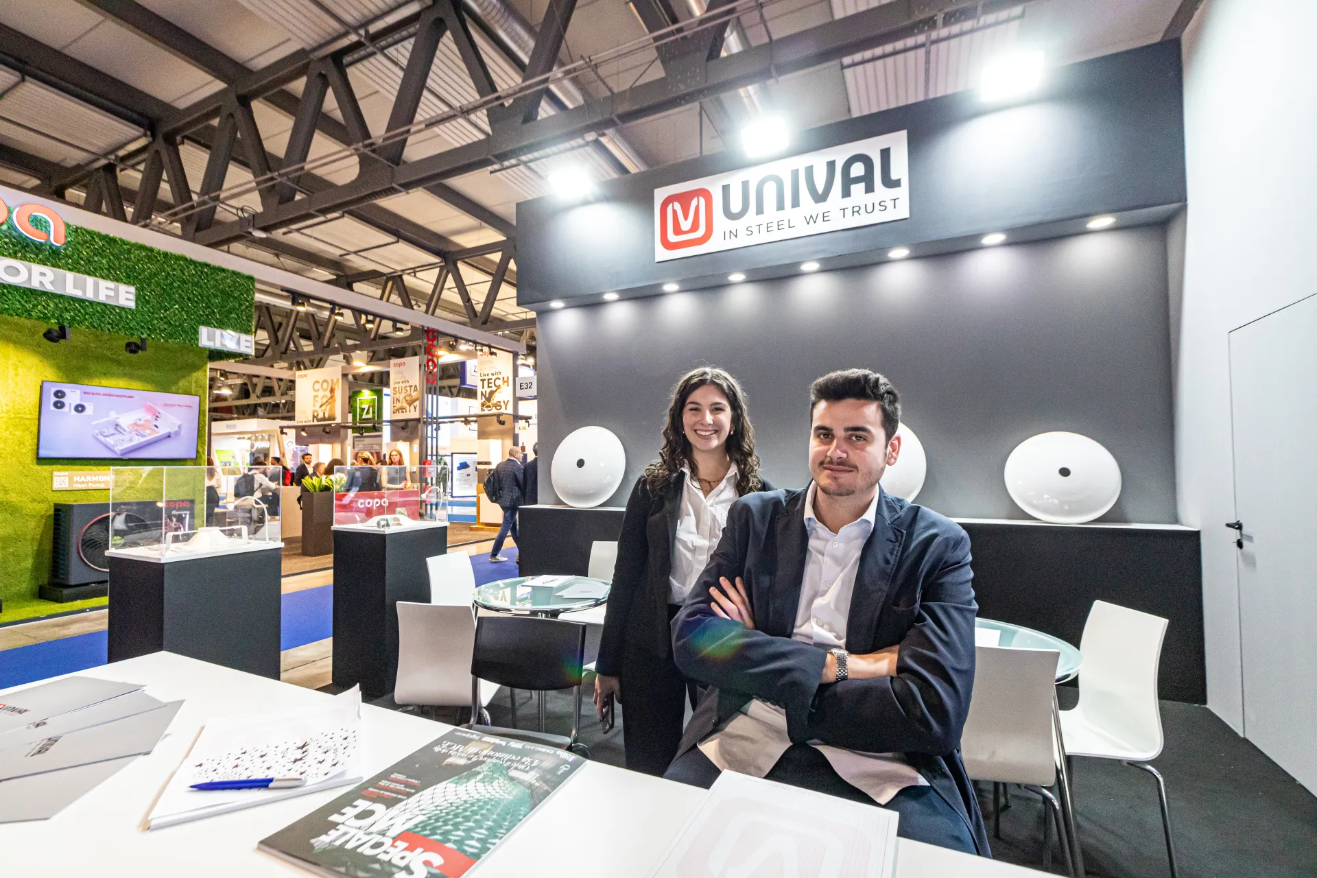 Unival desk with dished ends on the back wall and glass display cases at MCE 2024