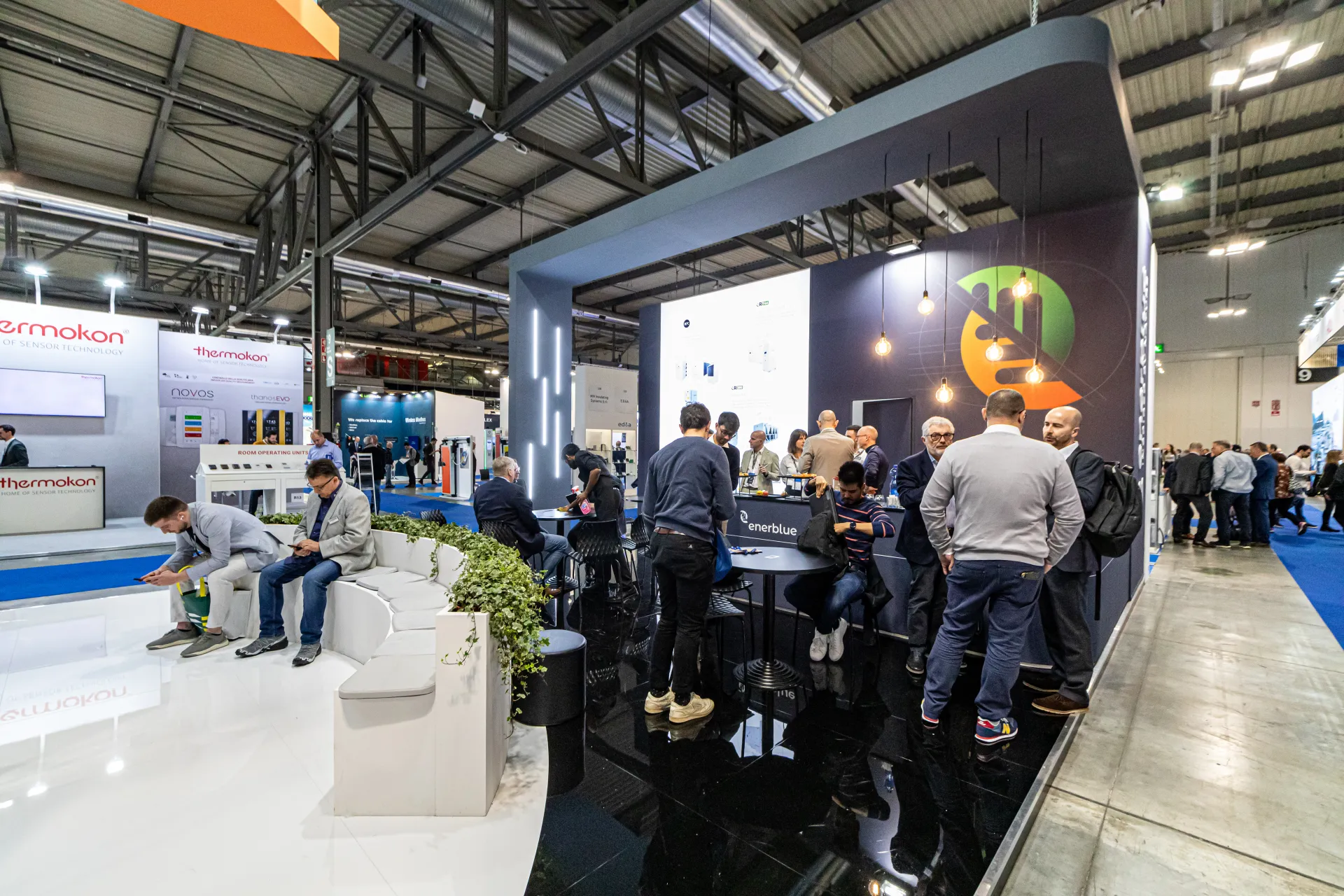 Visitors in the dark gloss meeting zone of the Enerblue stand at MCE 2024