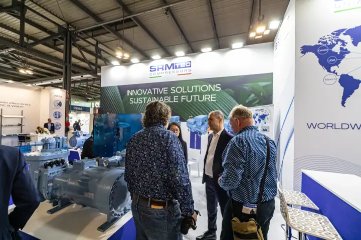 Visitors discuss a large grey compressor on the SRMTec stand at MCE 2024