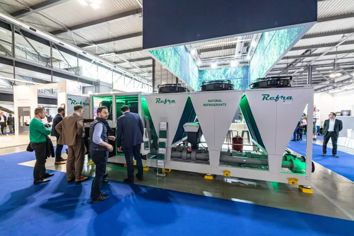 Visitors inspecting the Refra natural refrigerant unit under leaf canopy at MCE 2024