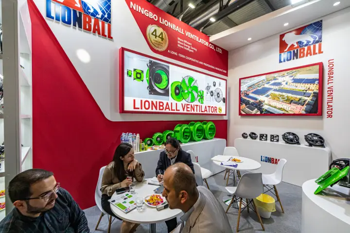 Visitors at Lionball meeting tables below the illuminated fan lightbox at MCE 2024