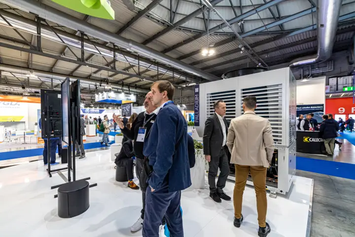 Visitors at vertical screens beside the Enerblue Palladium unit