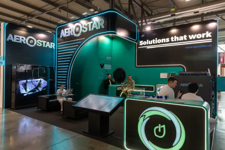 Aerostar stand in black and teal with neon lines and touchscreen table
