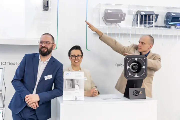 AFL Motors Europe staff pointing to the blower shelf above the counter at MCE 2026